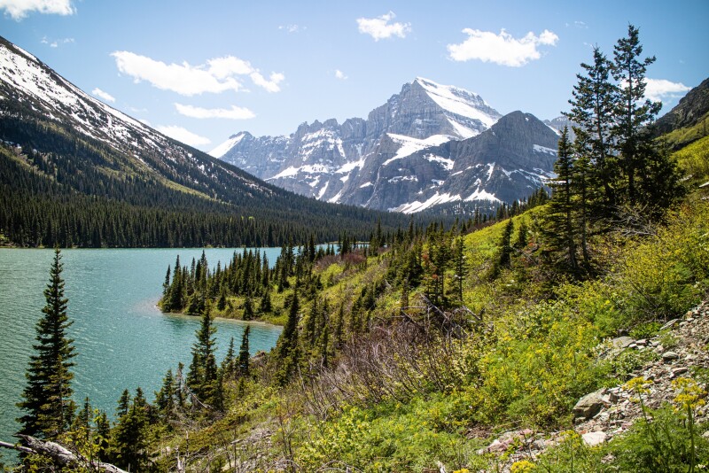 Mountains with patches of snow and forests beside Lake Grinnell
