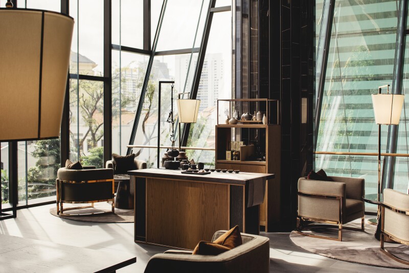 The lobby of the Clan Hotel in Singapore features neutral hues and a central table with standing lamps.