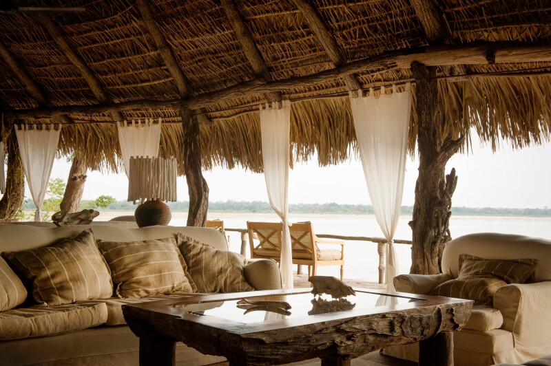 Seats and table beneath a straw roof, with river in distance