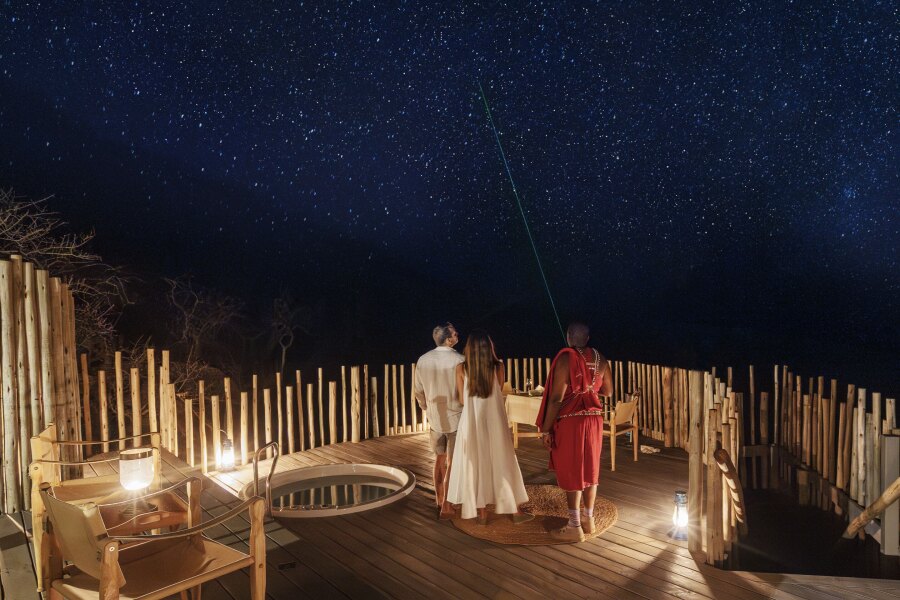 An outdoor lounge area at Saruni Basecamp, with two guests and a star guide at night