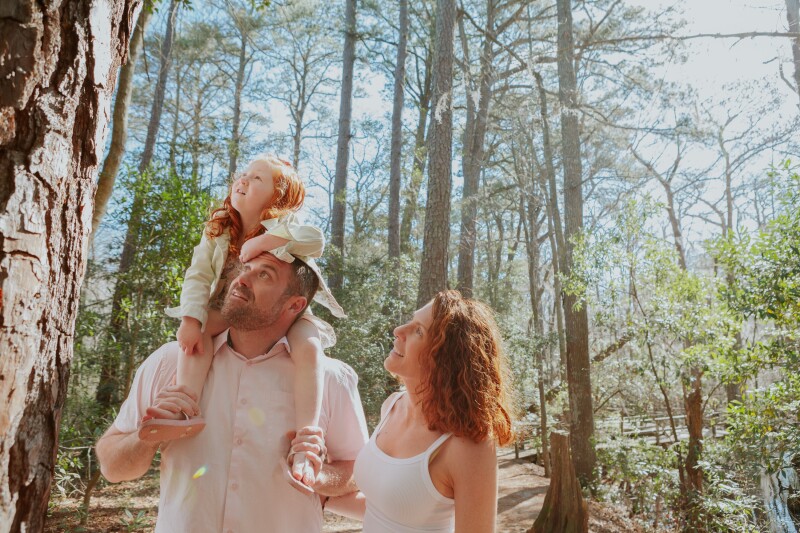 A family hiking. through the trees at First Landing State Park in Virginia Beach, Virginia.