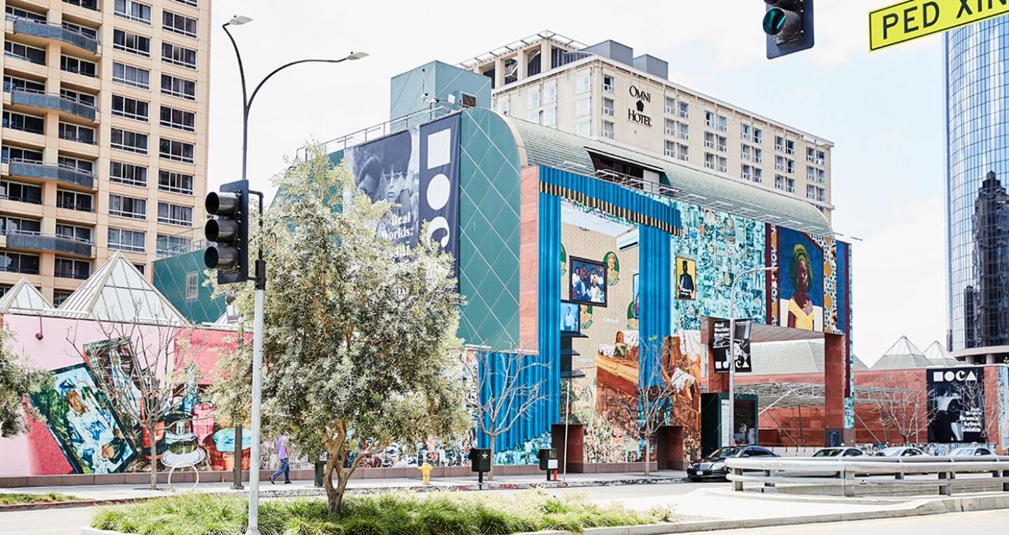 A museum in the city. Its streetside wall is covered in a large detailed mural.