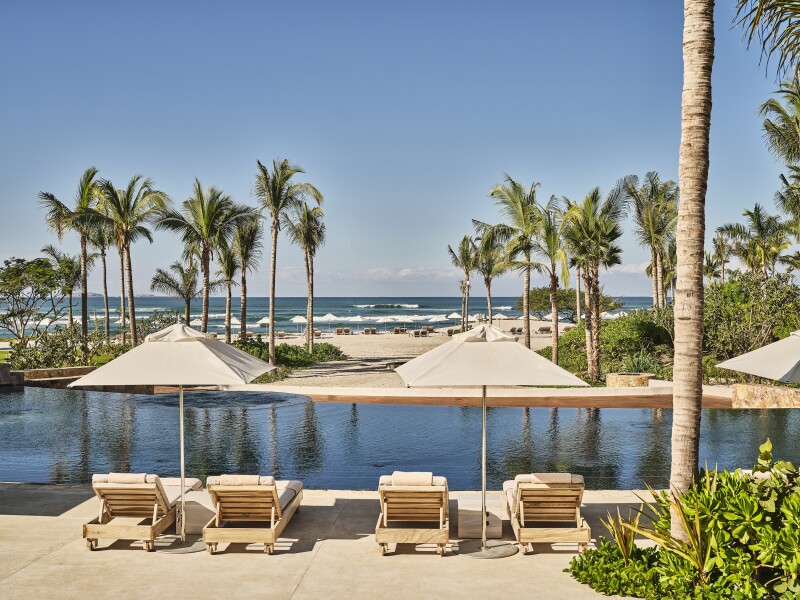 The pool at Susurros del Corazón is flanked by lounge chairs and faces the Pacific Ocean.