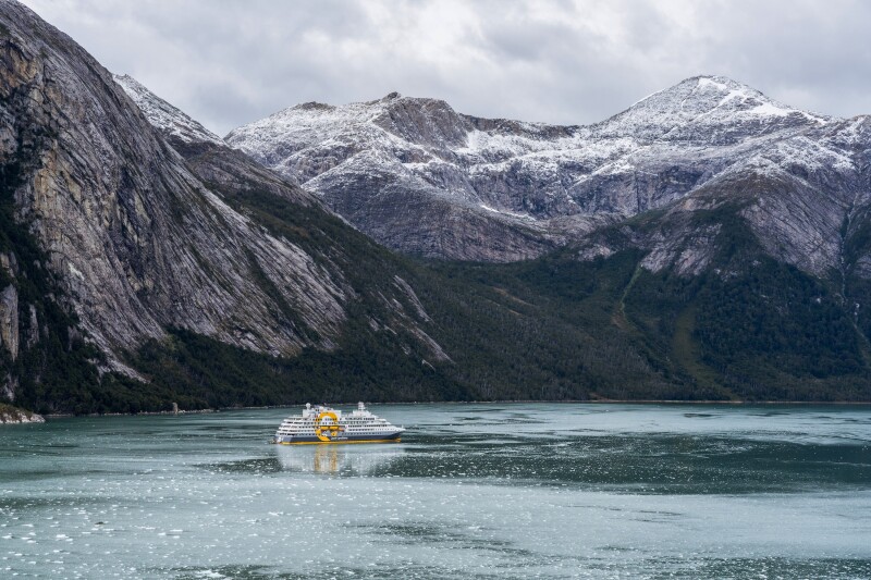 A Quark Expeditions vessel in the icy water of Patagonia with large snow-dusted mountains in the background