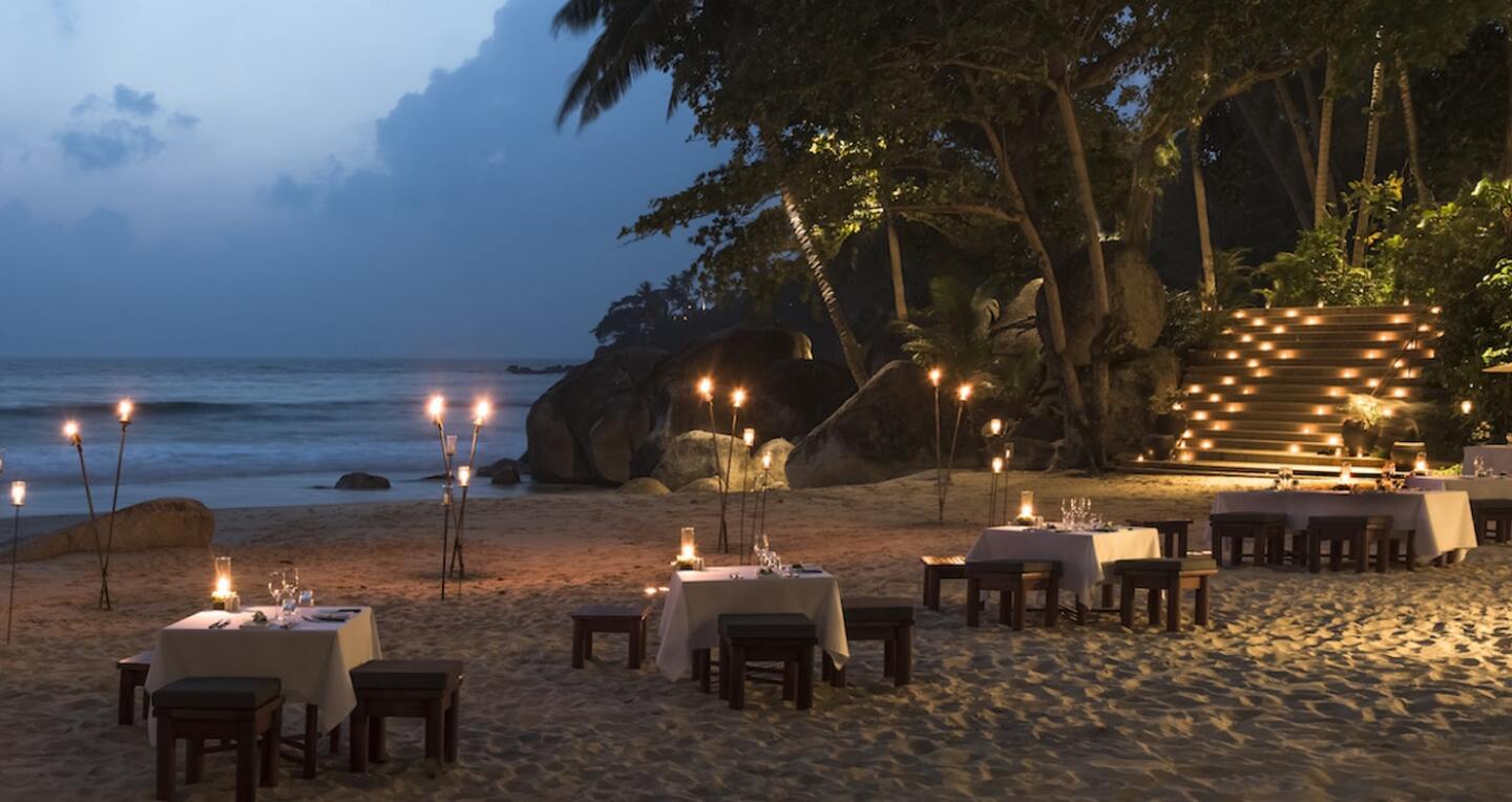 4 candlelit tables on the beach at twilight