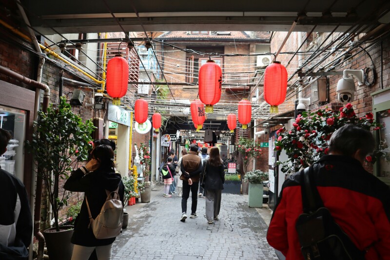 Red lanterns hanging over shoppers walking down a narrow street in The Tianzifang District, China