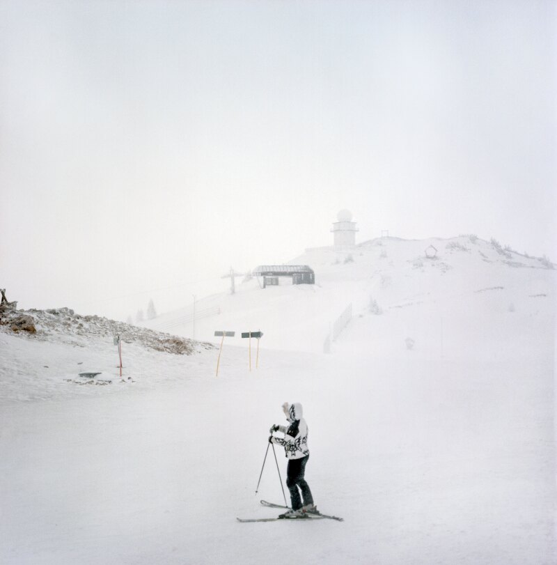 A skier at prepares for a run on a stormy day near the top of the Jahorina ski resort, in the Dinaric Alps, Bosnia and Herzegovina. Visible is the summit peak Ogorjelica (1916m).