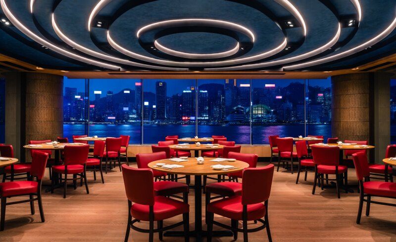 Nobu Hong Kong at the Regent Hong Kong, with crimson chairs, blond wood floors, and Victoria Harbour view shown at night
