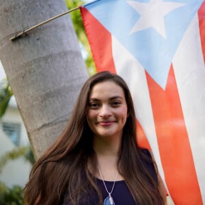 Jenn Ruiz in front of a Puerto Rican flag