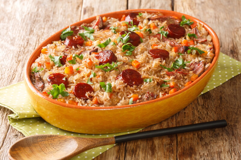 Un plato de arroz anaranjado cubierto con rodajas redondas de salchicha de pato