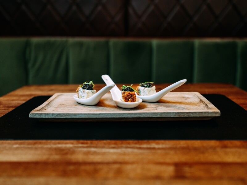 Appetizers on single serving spoons atop a wooden platter at Rye restaurant in Dallas, Texas
