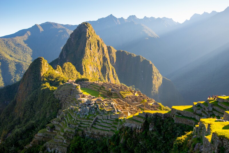 Aerial view of Machu Picchu in Peru, with ruins visible on a plateau, and mountains in background