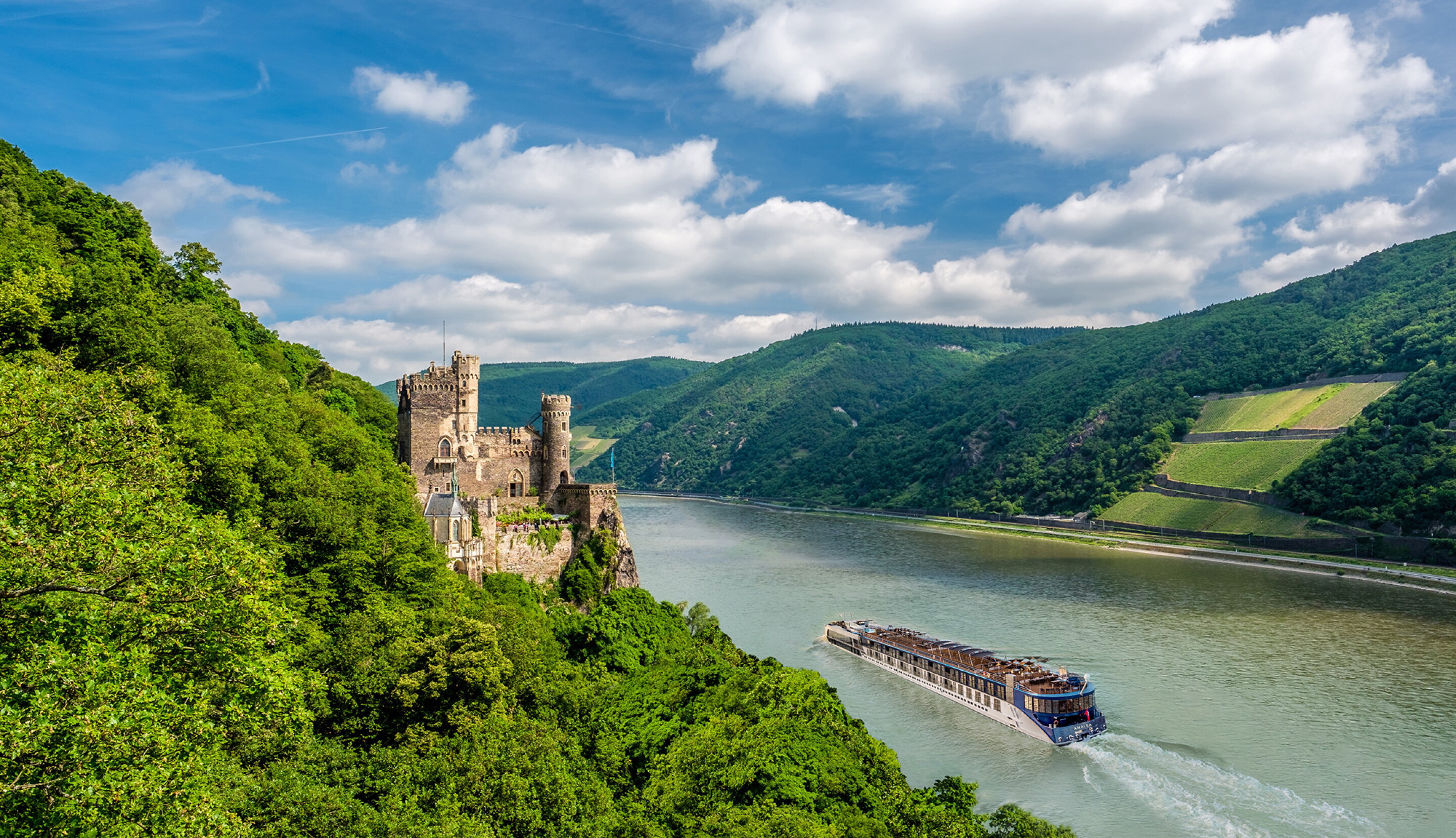 River cruise ship winding past hills and Rhine castles