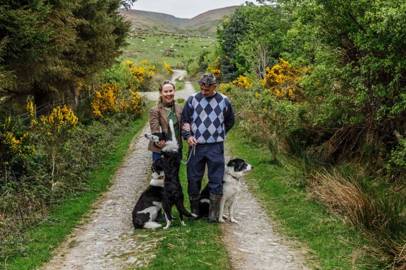 Catherine and James Powers in a rural landscape with three balck-and-white border collies