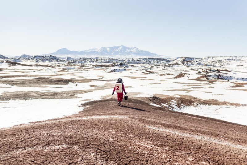A member of a MDRS simulation team from The International Space University in Strasbourg strides out into the Utah desert. During the summer months many teams live and work at the Mars Desert Research Station. The terrain’s ferrous-red hue and the harshness of the climate are used to mimic Mars’s. Each crew carries out experiments ranging from astrobiology and meteorite analysis to 3D-printing and social psychology.