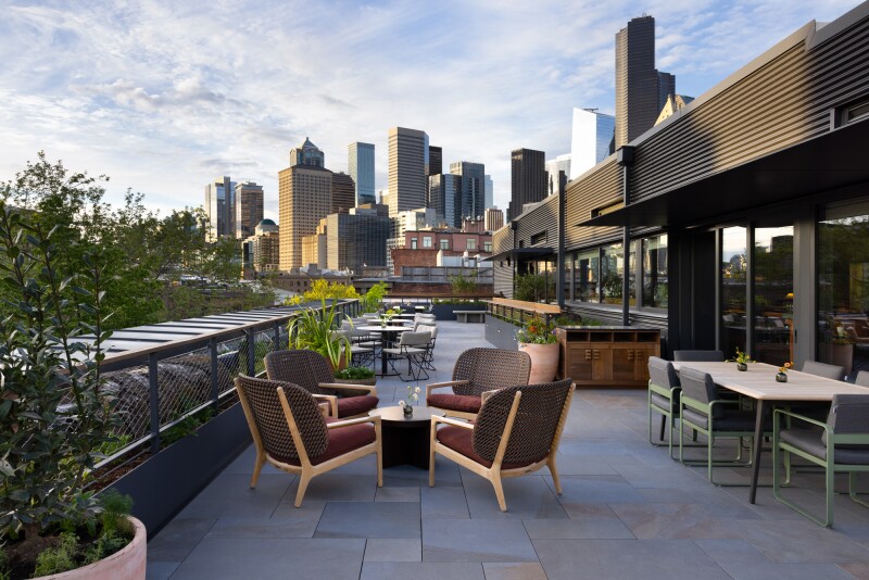 Small groups of chairs and tables at Firn rooftop bar, with views of downtown skyline