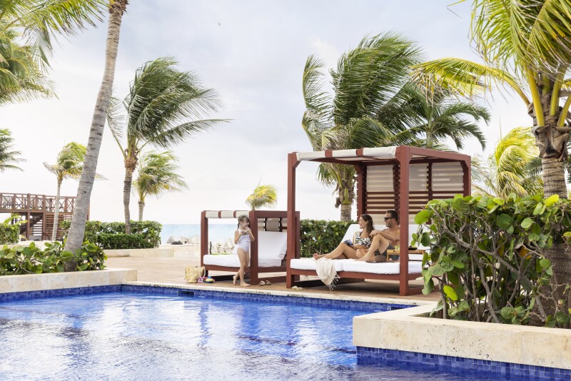 Hyatt Ziva Cancun's pool, with two cabanas, one kid-size, among pam trees