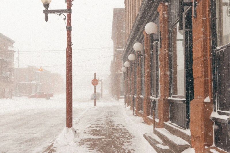 An empty city sidewalk during a snowstorm