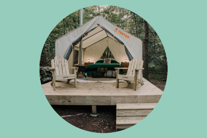 Interior of glamping tent, with 2 Adirondack chairs in front on wood deck