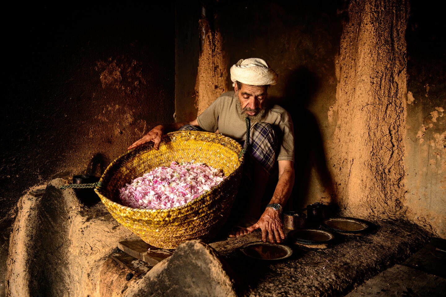 Man in turban holding large basket full of pink petals