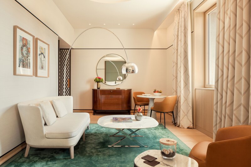 This Junior Suite at the Bulgari Hotel Roma features a green carpet and sleek midcentury-inspired furnishings.