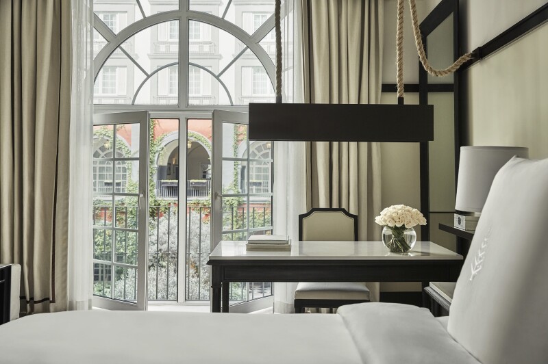 A white guest room at the Four Seasons Hotel Mexico City, with a marble-topped desk and glass doors opening to balcony