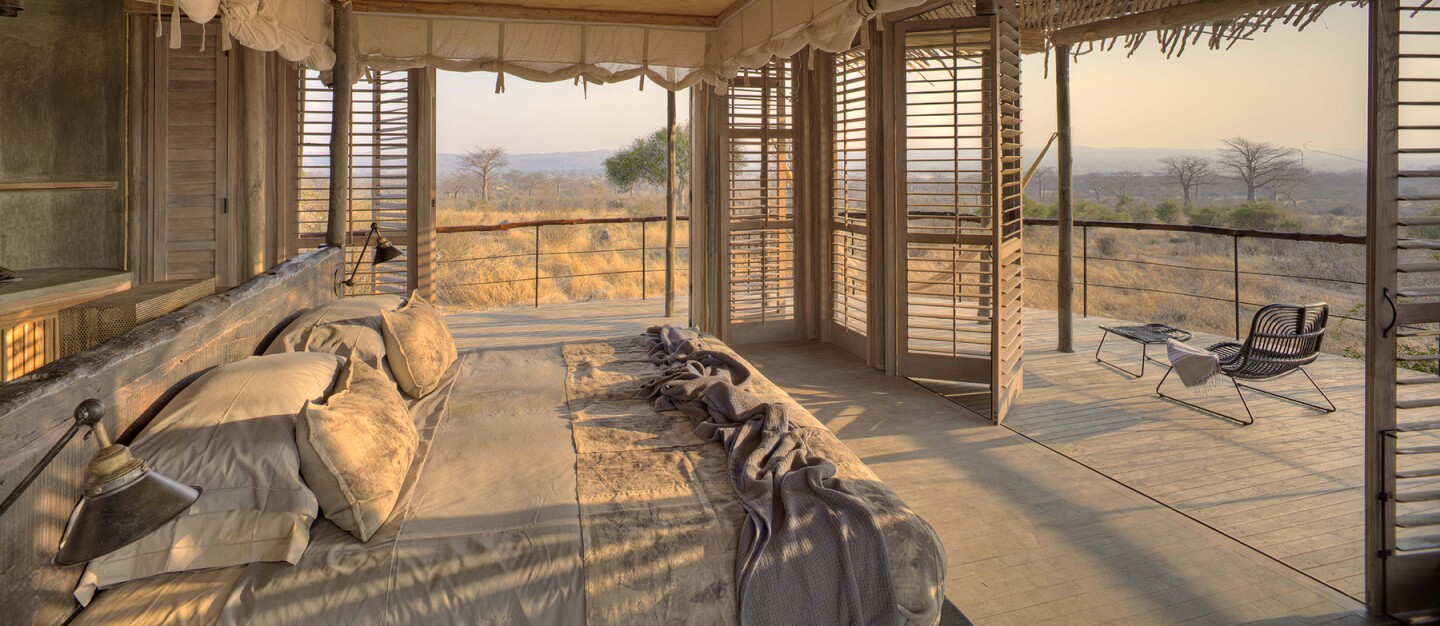 Interior of a Jabali Ridge guest room, in neutral beige, with views of Ruaha National Park