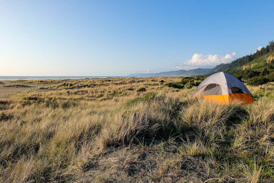 Lone gray and orange tent on grassy dunes