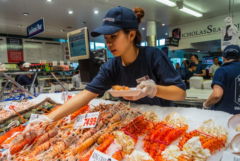A vendor selects crustaceans from rows on ice for a buyer in Sydney Fish Market