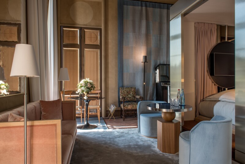 Guest room at Cour des Vosges with peach-colored sofa and gray rounded chairs and carpet