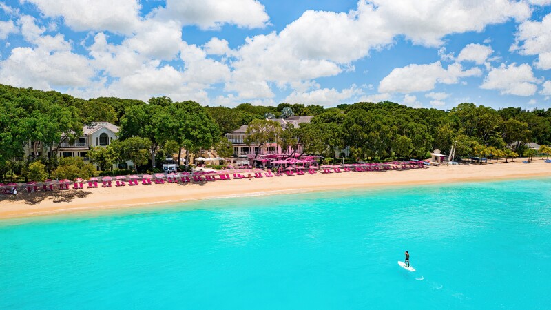 Sandy Lane beach resort in Barbados, beachfront resort with a person on a SUP in the ocean.