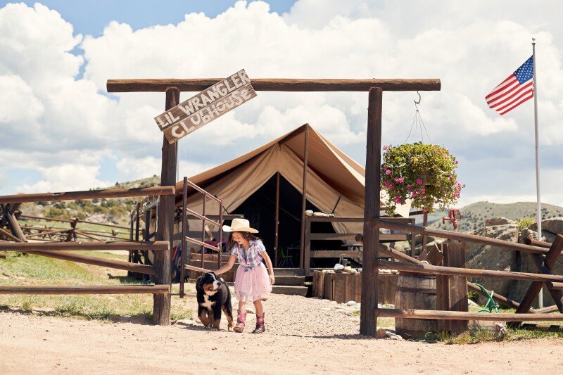 Exterior of the Lil Wrangler kids club at Brush Creek Ranch with girl and dog