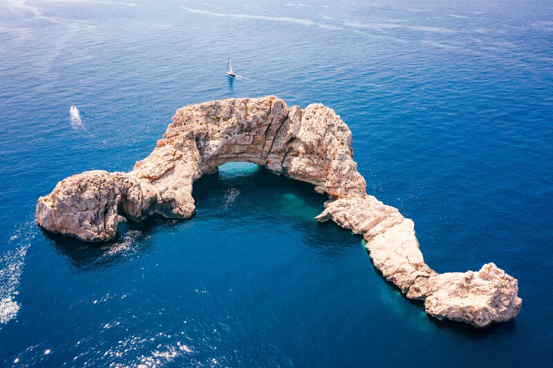 Aerial view of curved "Gates of Heaven" rock formation in Balearic Sea