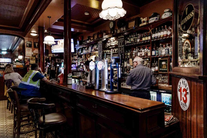 A mahogany bar with a barkeep and a couple of patrons