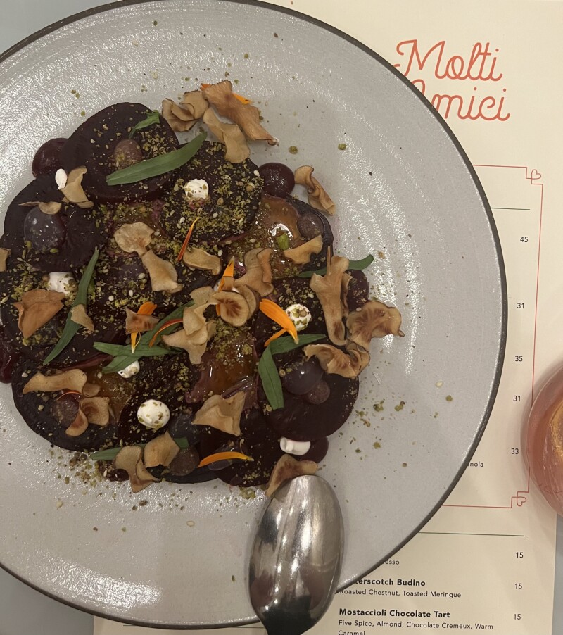 Overhead view of white dish of pasta atop menu for Molti Amici