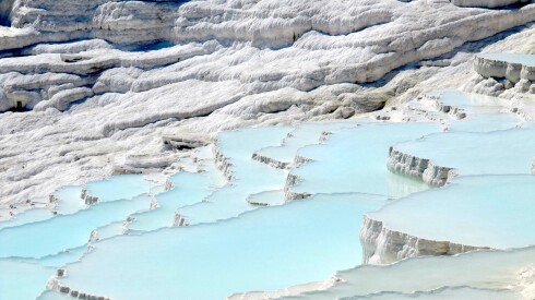 Terraced pools with milky blue waters surrounded by chalky white stone