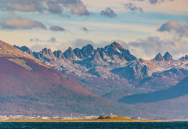 A view of peaked mountains with a small amount of snow in Puerto Williams, Chile, with the Beagle Channel in the foreground