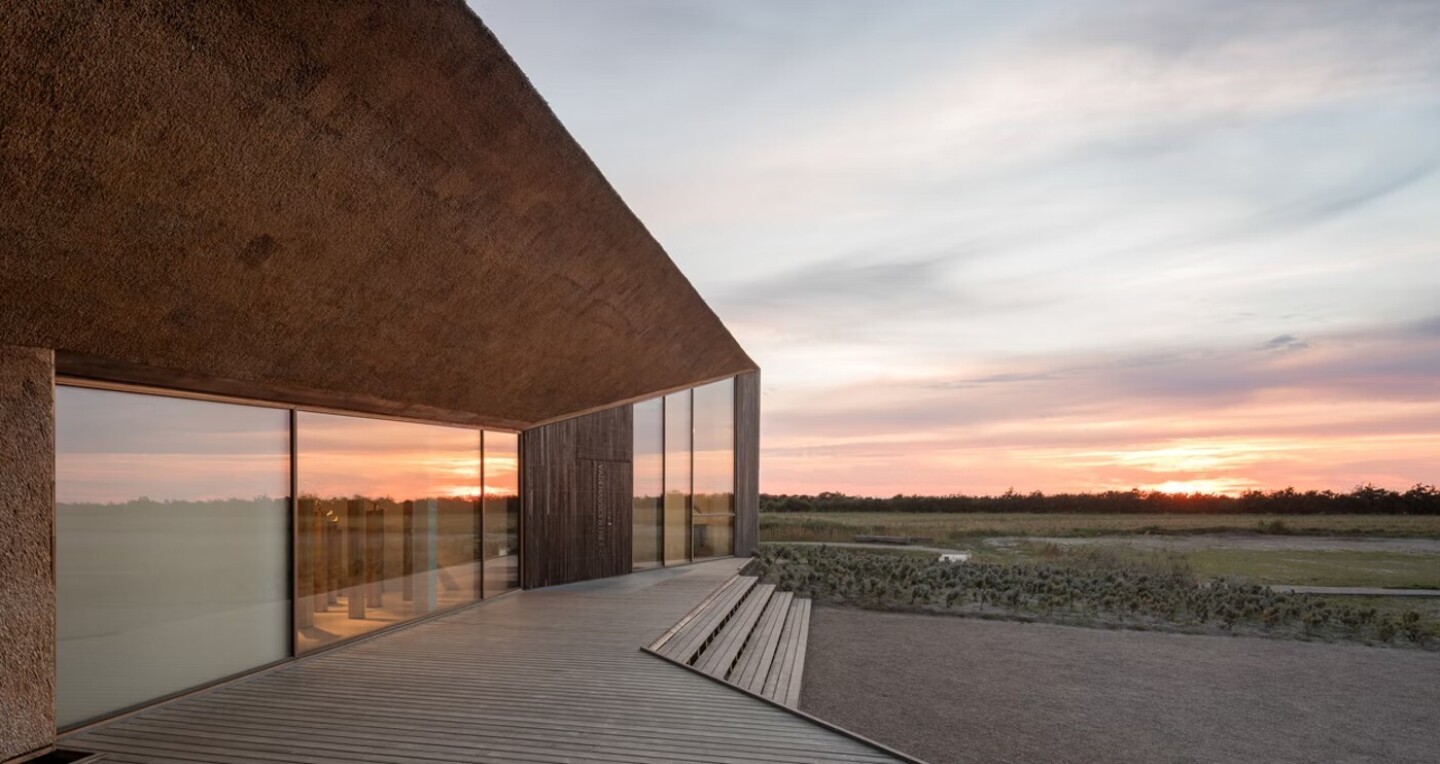 A modern mansion on a flat plain at sunset.