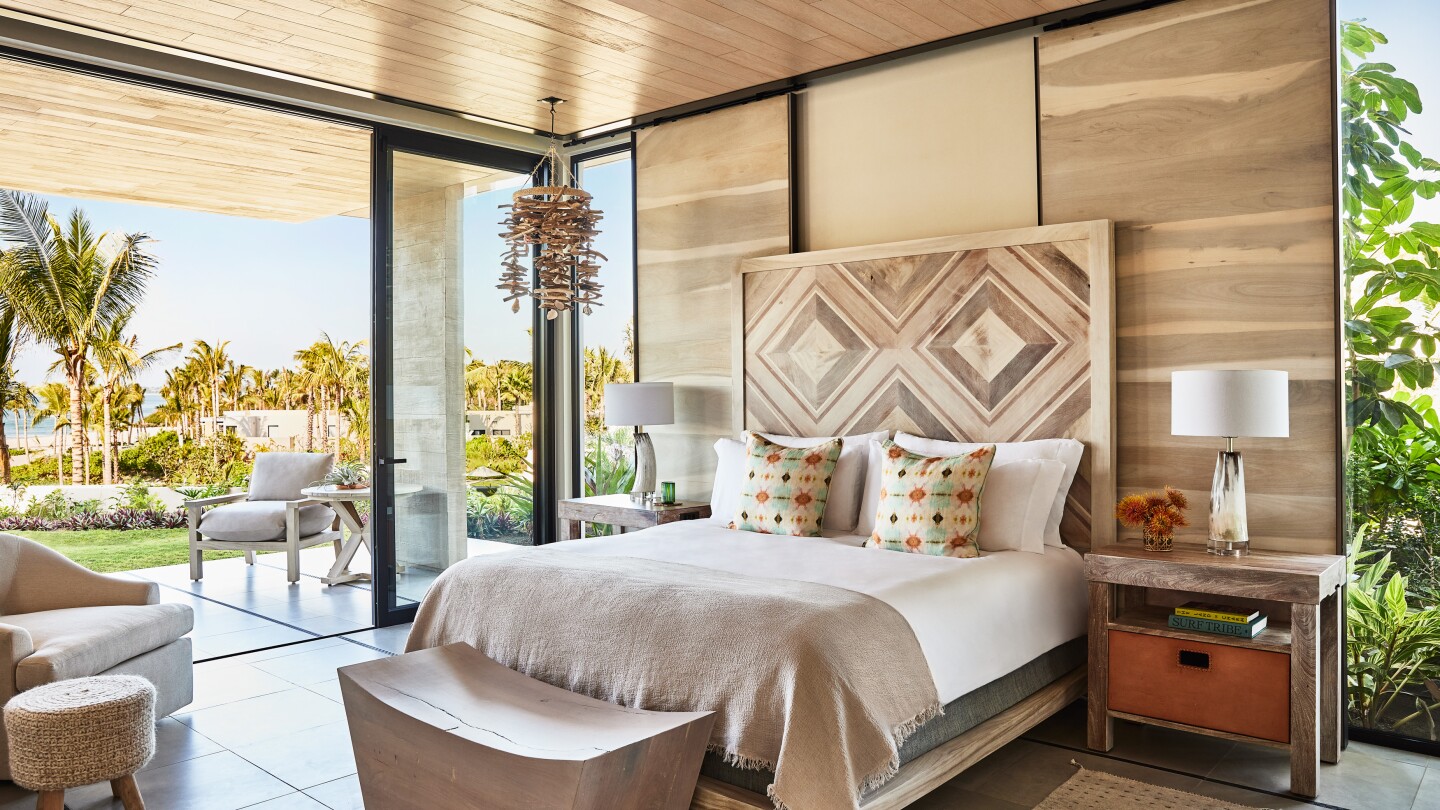 This Garden Studio guest room at Susurros del Corazón features a large bed with an inlaid wooden headboard and a terrace facing the Pacific Ocean.